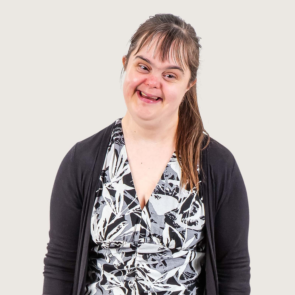 Kim - A young woman with Downs syndrome, she wears a black and white blouse with black cardigan.
