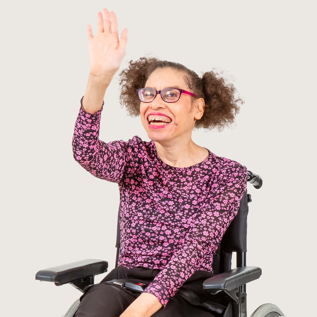 Mariah - A young disabled woman with British and Ghanaian  heritage. She uses a wheelchair and wears bright pink top with matching red glasses.