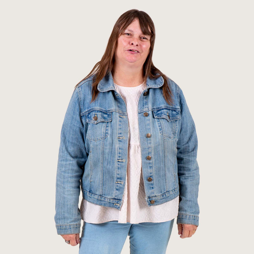 Amy - a middle aged white woman with long hair. She is wearing a denim jacket and jeans.