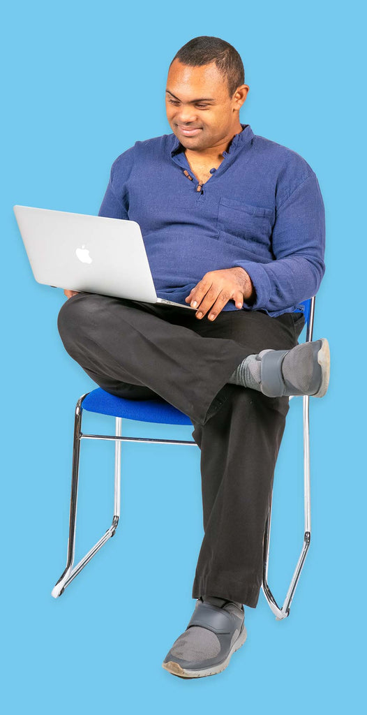 A man sits in a chair looking at a laptop.