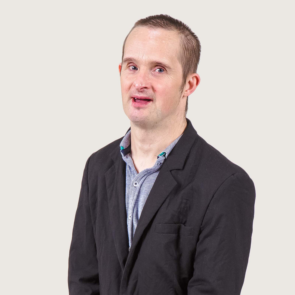 Finn - A middle aged man with Downs syndrome, wearing a smart shirt and suit jacket.