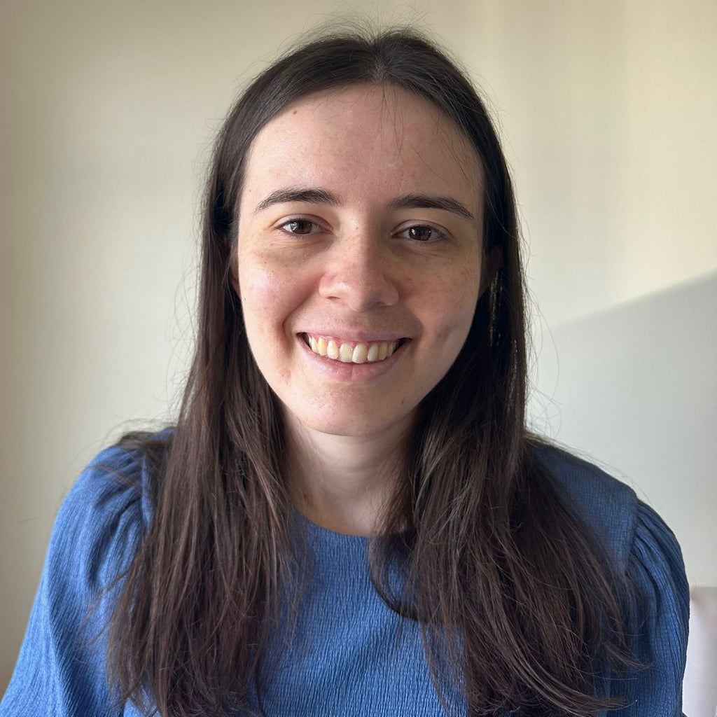 Grace has long brown hair and wears a blue shirt.