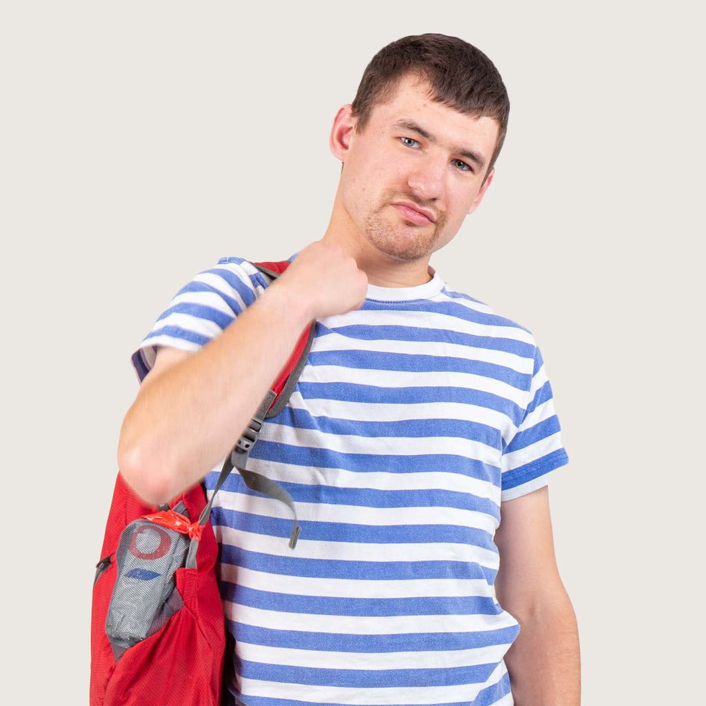 Kevin - A young white man wears a white and blue striped T-shirt with a red rucksack slung over his shoulder.