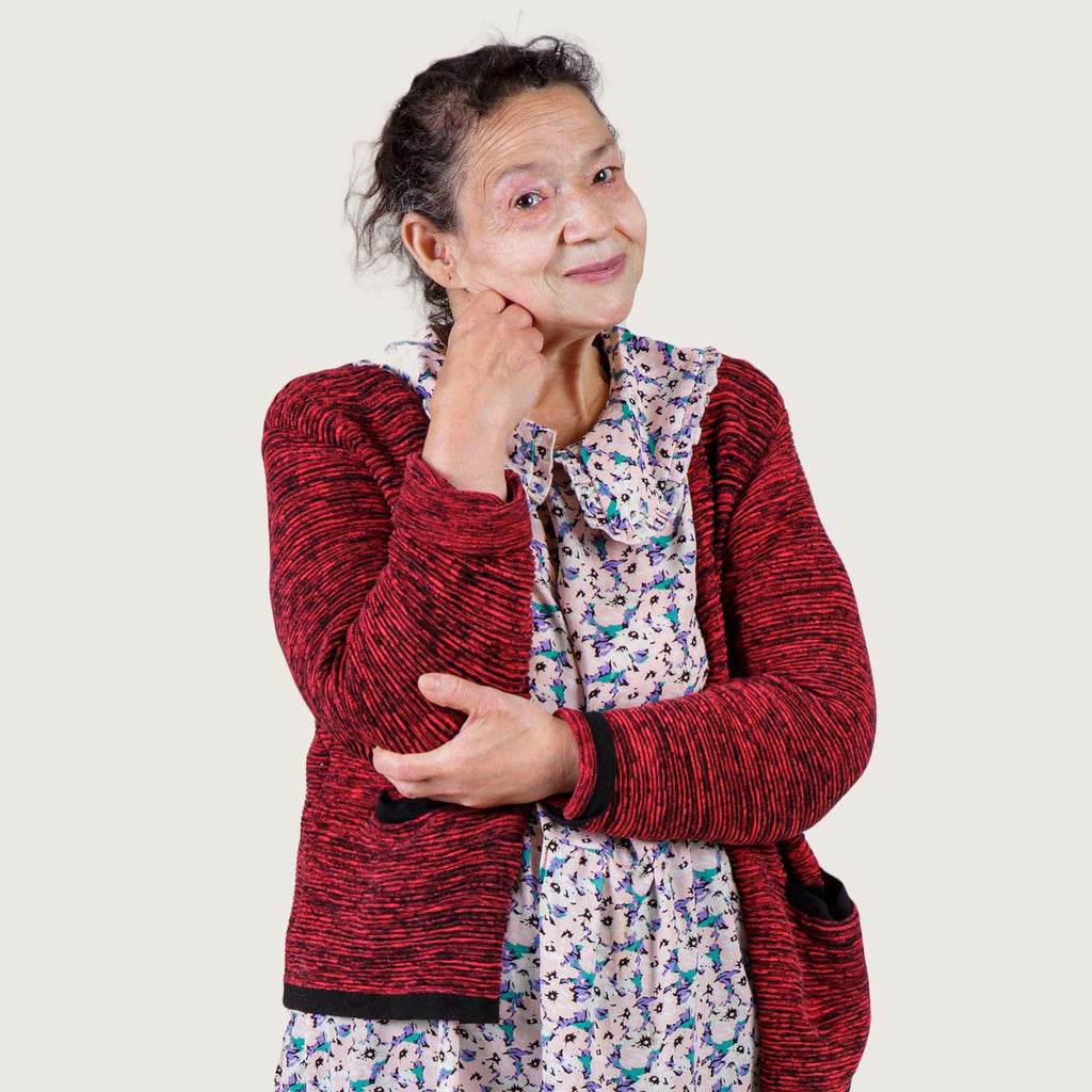 Margory - An older white woman wearing a colourful blouse and a red cardigan.