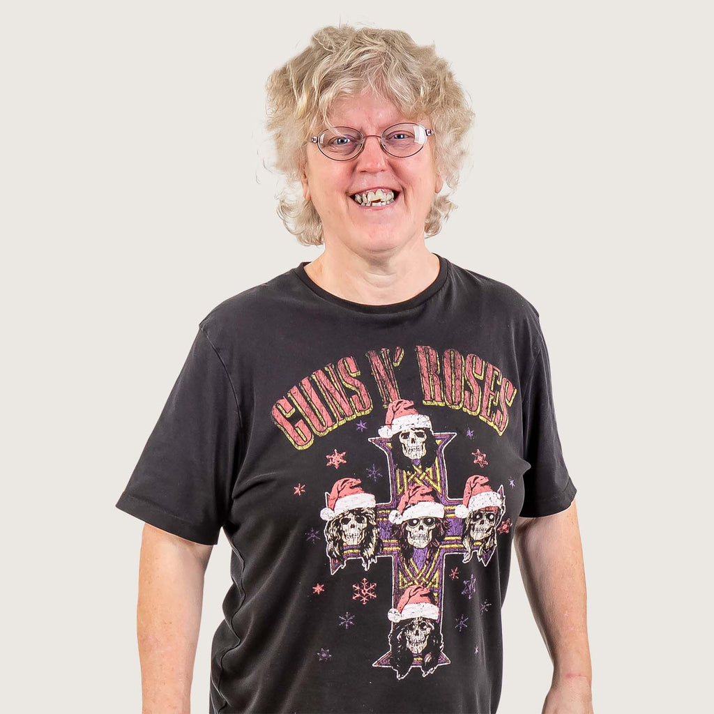 Marta - A white woman with white wavy hair and glasses, she wears a Guns N Roses T-Shirt.