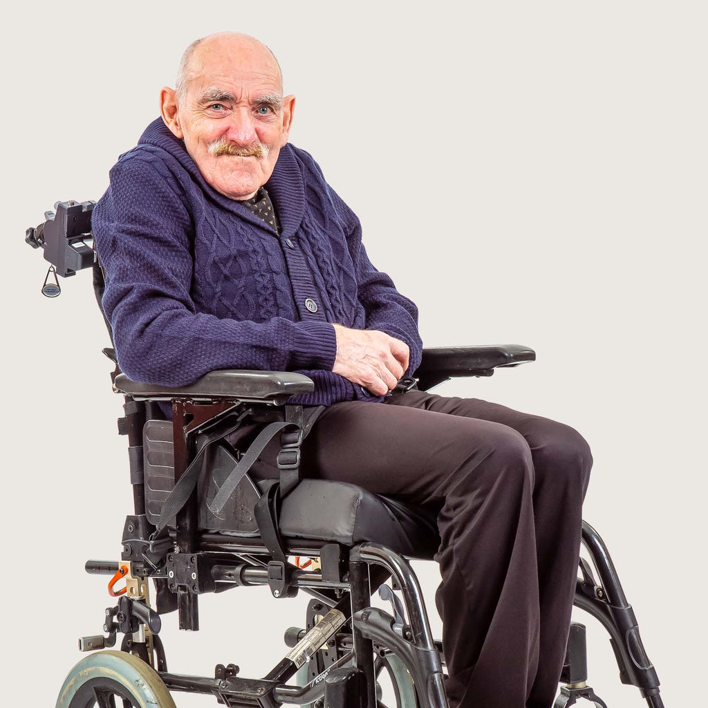 Vinnie - An older white gentleman with short cropped hair and a moustache who uses a wheelchair. He wears a blue cardigan and black trousers.