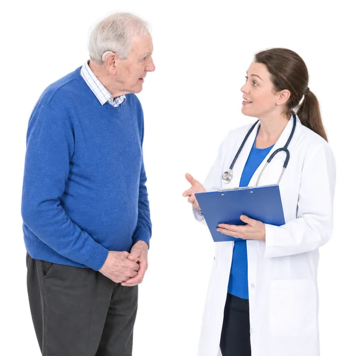 A doctor holding a clipboard talking with an older man in a blue jumper.