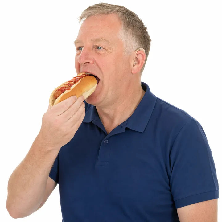 A man taking a bite of a hot dog.