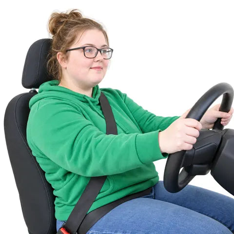 A young woman with glasses and a green hoodie, both hands on the steering wheel.