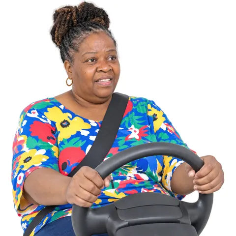 An older woman in a bright flowery top, holding the steering wheel.